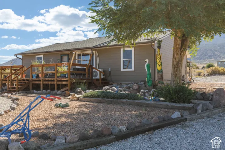Exterior featuring a multi-level wood deck, neutral-toned siding, and a gravel landscape with rock borders