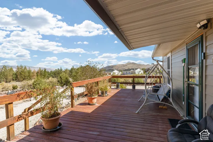 Expansive outdoor deck with wood railing, covered patio area, and exterior lighting