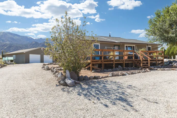Expansive gravel driveway leading to a two-car garage and a large wooden deck