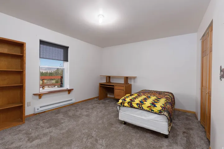 Light-filled room featuring a broad window, white walls, and gray carpet flooring