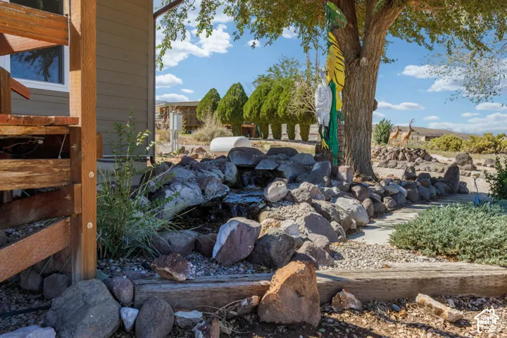 Rock water feature with natural stone landscaping, mature tree, and gravel ground cover