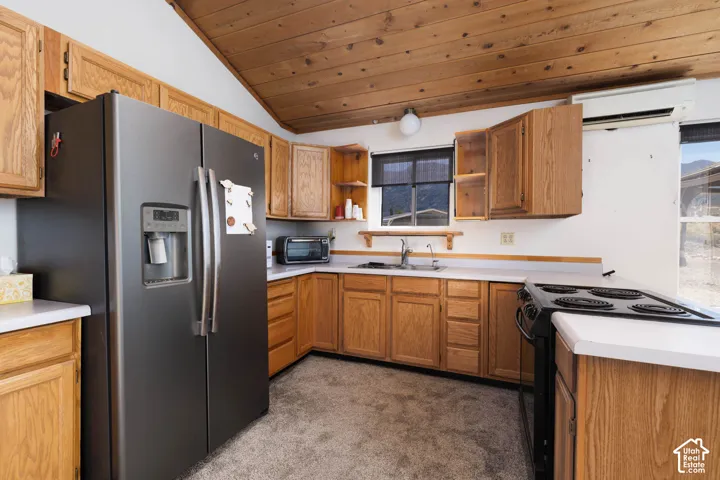 Kitchen featuring wood cabinetry, white countertops, stainless steel refrigerator, electric range, and wood-paneled ceiling