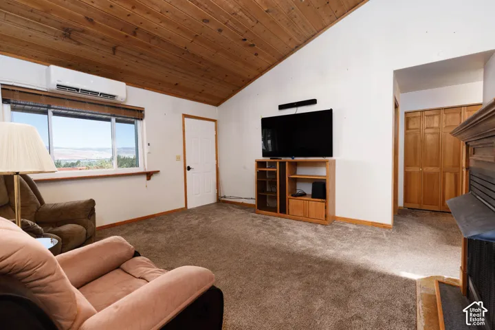 Vaulted wood-paneled ceiling, large window, built-in air conditioning unit, and wood-finish bi-fold closet doors