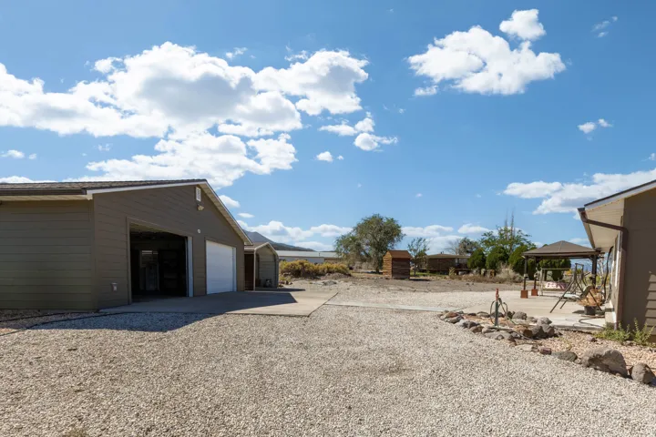 Detached garage building with multiple bays, gravel driveway, concrete pad, and a separate patio area with a gazebo