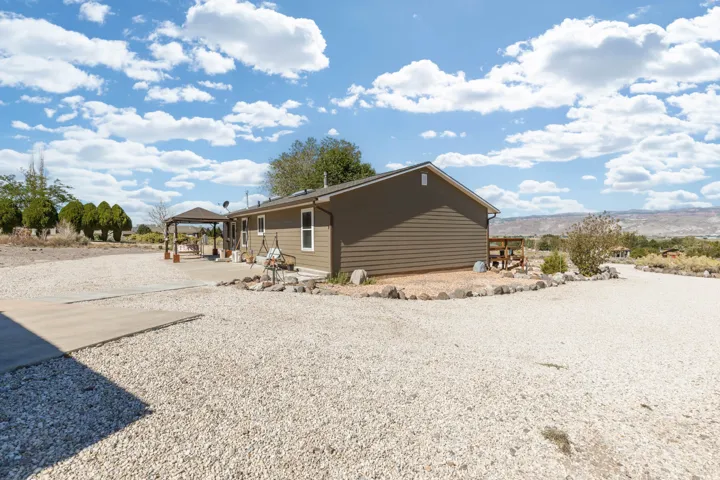 Single-story exterior with horizontal siding, gravel landscaping, a concrete patio, and an attached gazebo
