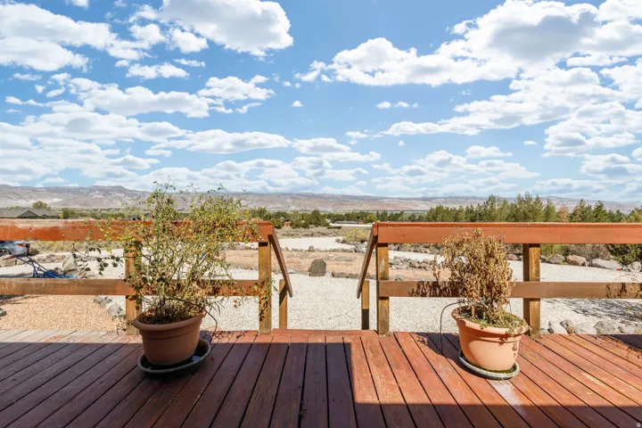 Wood-finish deck with a rustic wooden railing and expansive natural landscape