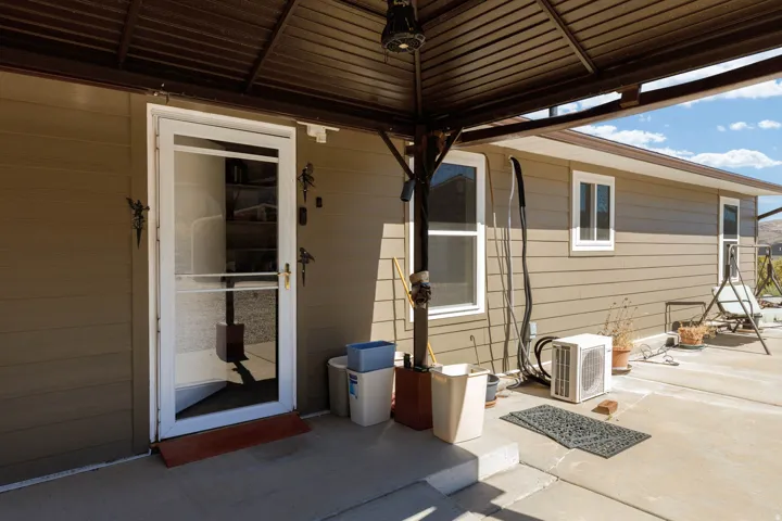 Covered patio featuring a concrete surface, white screen door, and light brown siding