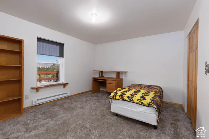 Light-filled room featuring a broad window, white walls, and gray carpet flooring