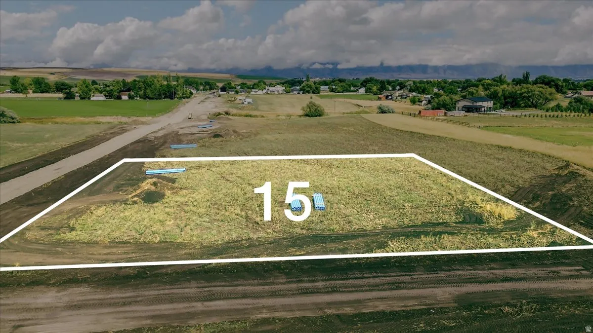Expansive land parcel with surrounding agricultural fields, distant mountain range, and scattered residential structures