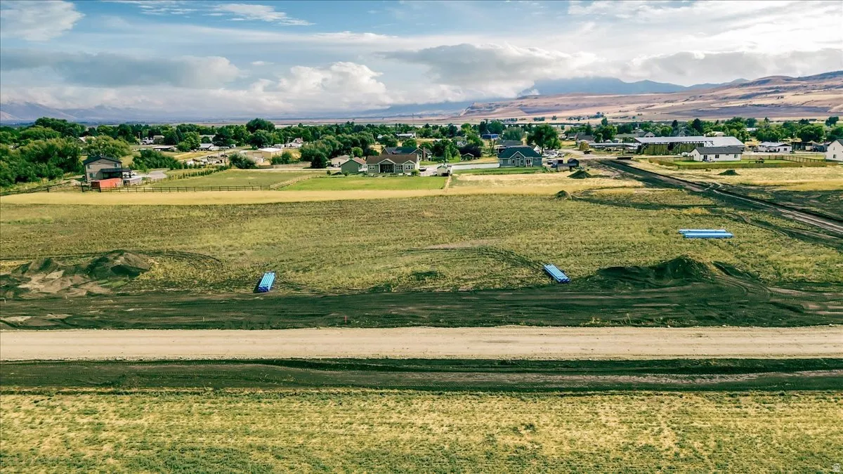 Expansive rural landscape featuring a dirt road and distant residential structures
