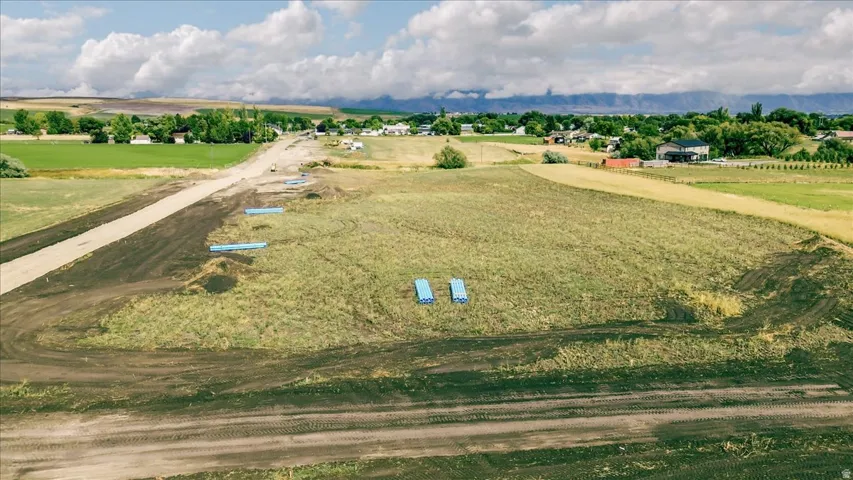 Expansive undeveloped land featuring a partial graded road and distant mountain range backdrop