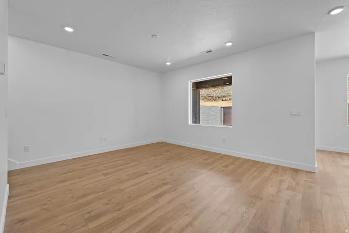 Recessed lighting, wood-finish flooring, and white walls with white trim