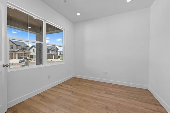 Light-filled room featuring wood-finish flooring, white walls, and recessed lighting