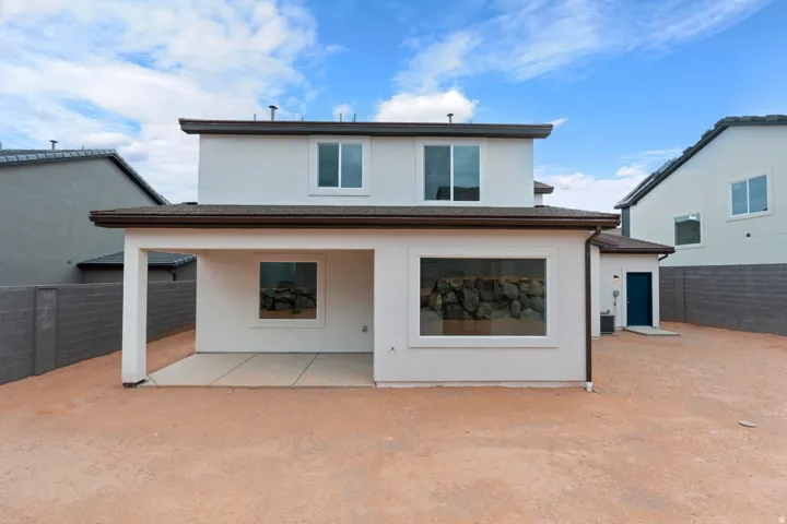 White stucco exterior with a covered patio, two-story construction, and a dark blue entrance door