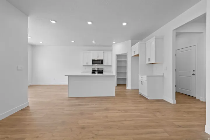 Open-concept living space featuring wood-finish flooring, recessed lighting, and a kitchen island with integrated sink