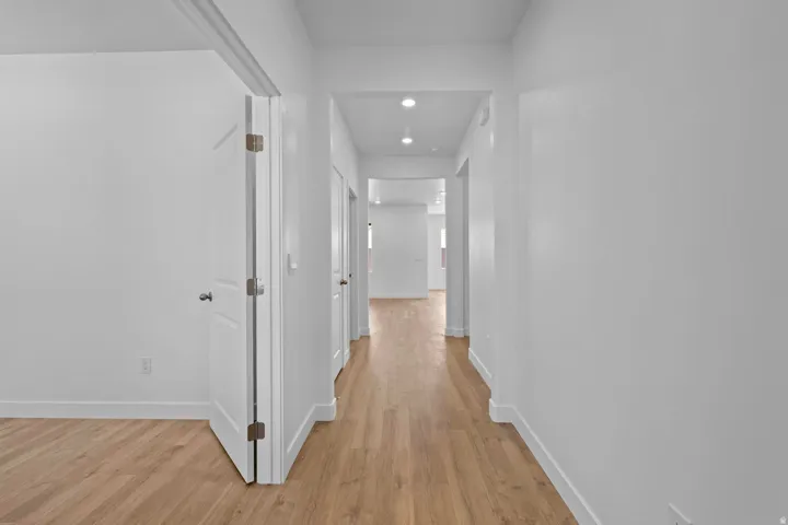 Hallway with wood-finish flooring, recessed lighting, and white trim