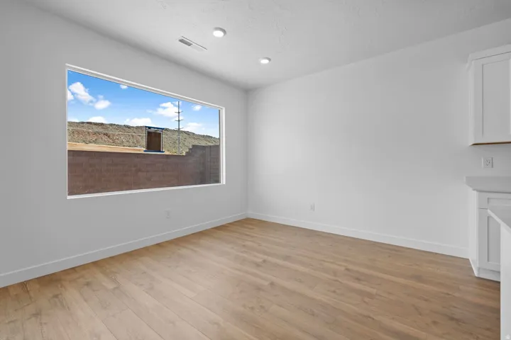 Wide window, wood-finish flooring, recessed lighting, white walls, built-in cabinetry