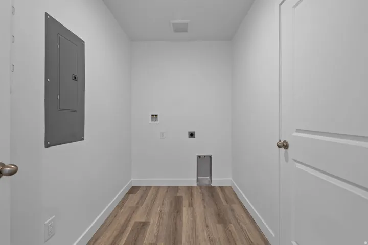 Dedicated utility space featuring wood-finish flooring, white walls, and a panel door