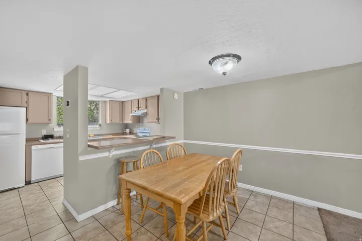 Kitchen with light cabinetry, white appliances, and a pass-through counter