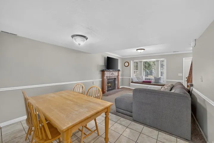 Recessed fireplace with brick surround, bay window with integrated seating, tile flooring, crown molding, and two ceiling-mounted light fixtures