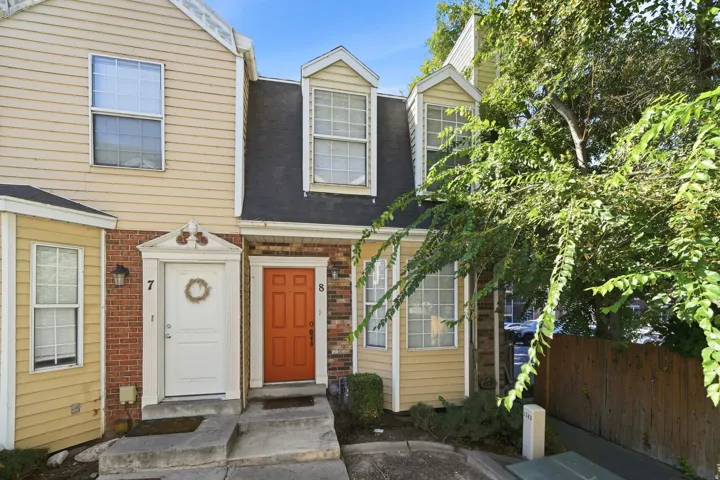 Multi-level facade featuring yellow siding, dormer windows, and an orange entry door