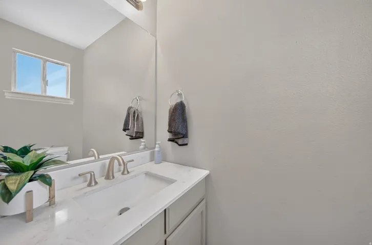 Bathroom vanity with an integrated sink, brushed nickel faucet, and a large mirror