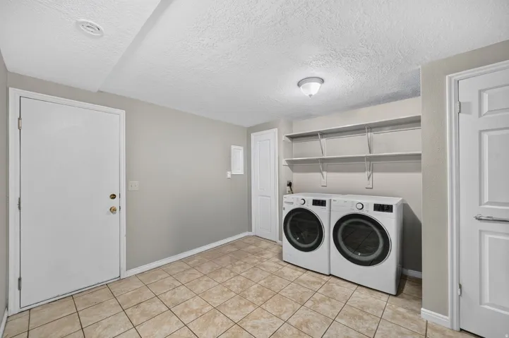 Utility room with tile flooring, built-in shelving, and light gray wall paint