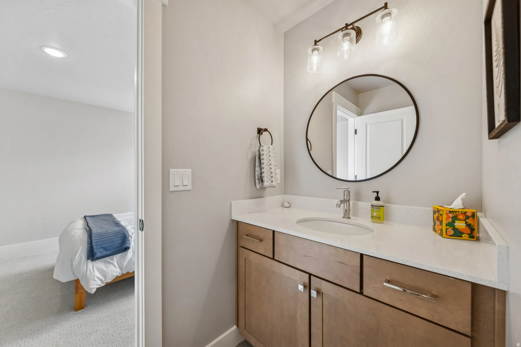 Bathroom vanity featuring a light-toned countertop, integrated sink, and wood-finish cabinetry with silver-toned hardware