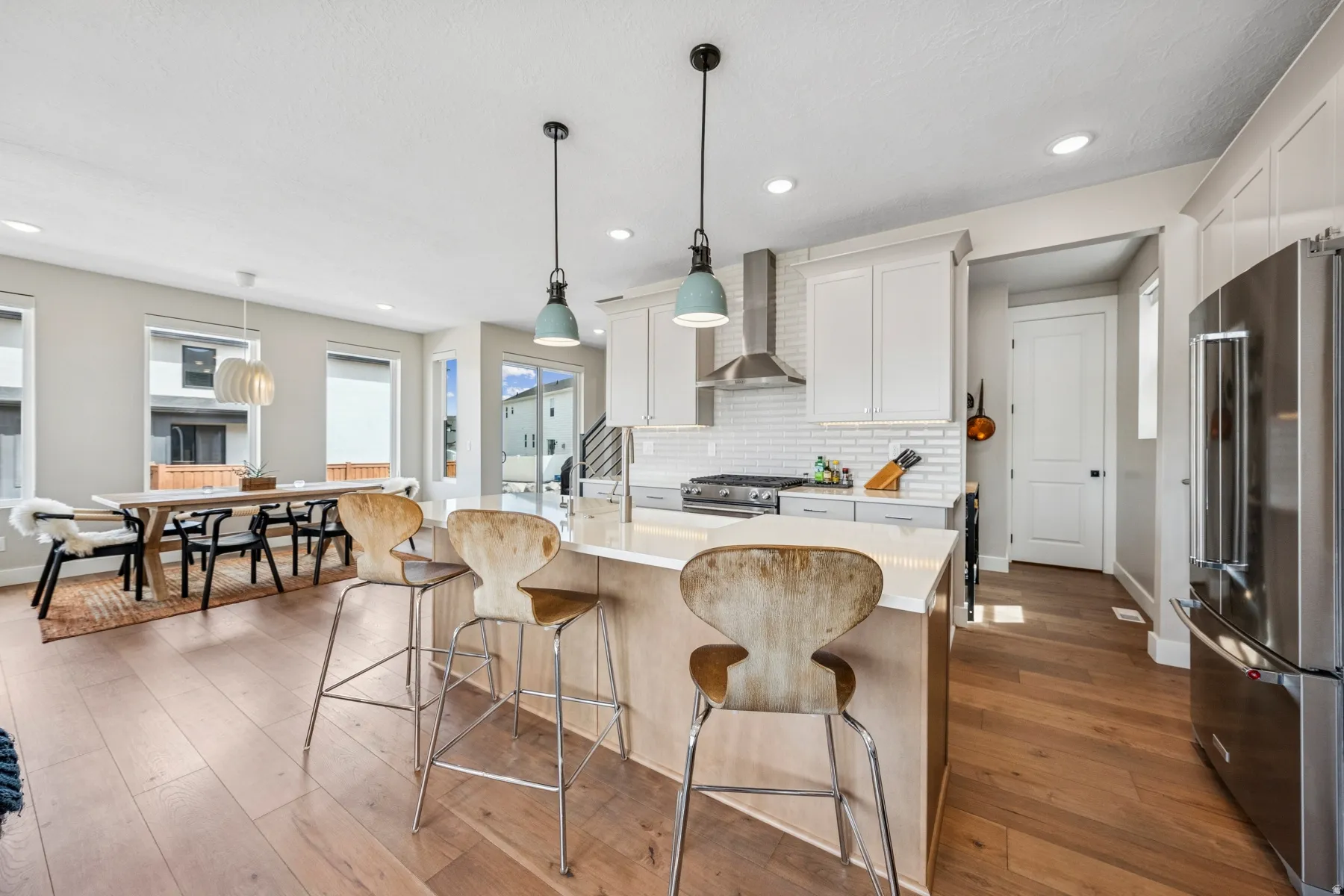 Kitchen with island seating, white cabinetry, stainless steel appliances, and subway tile backsplash