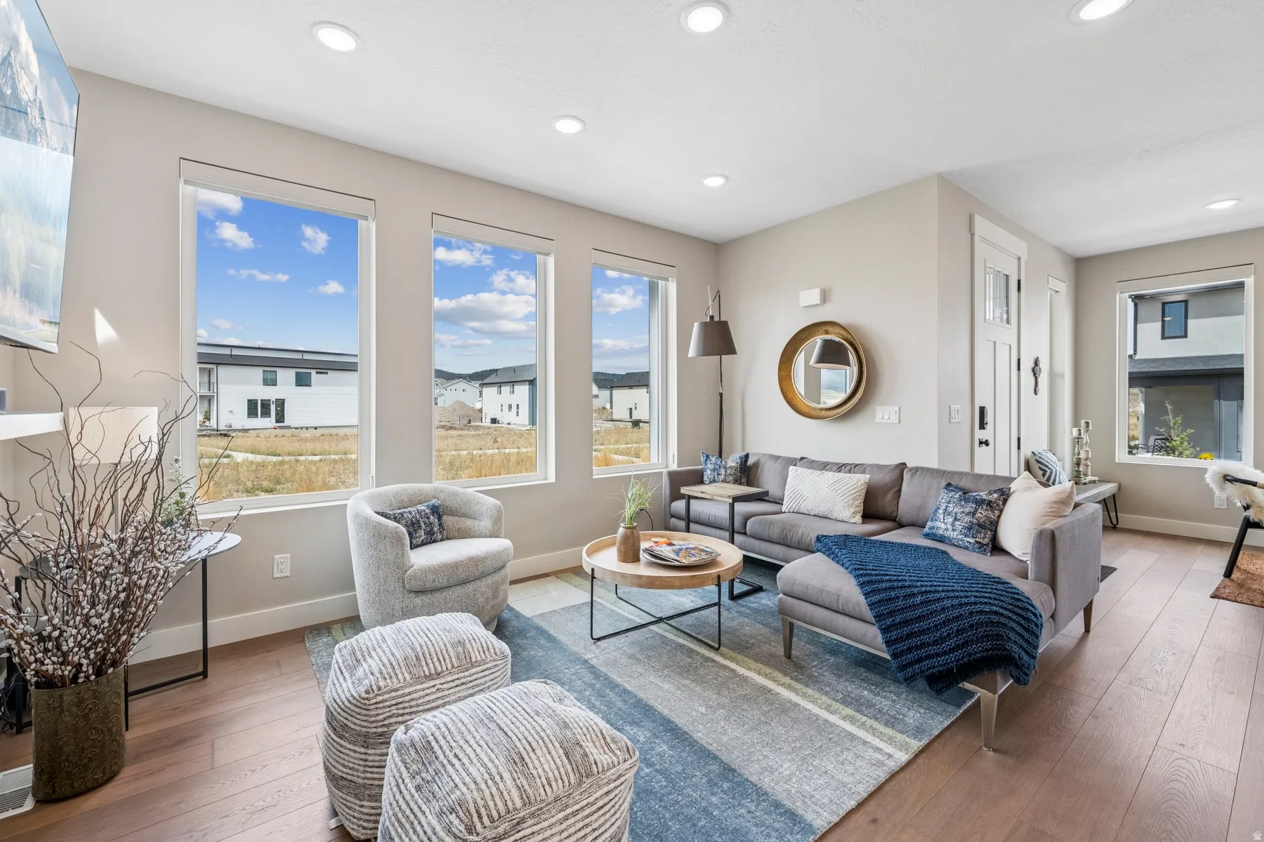 Open-concept living space with light wood-finish flooring, recessed lighting, and expansive windows