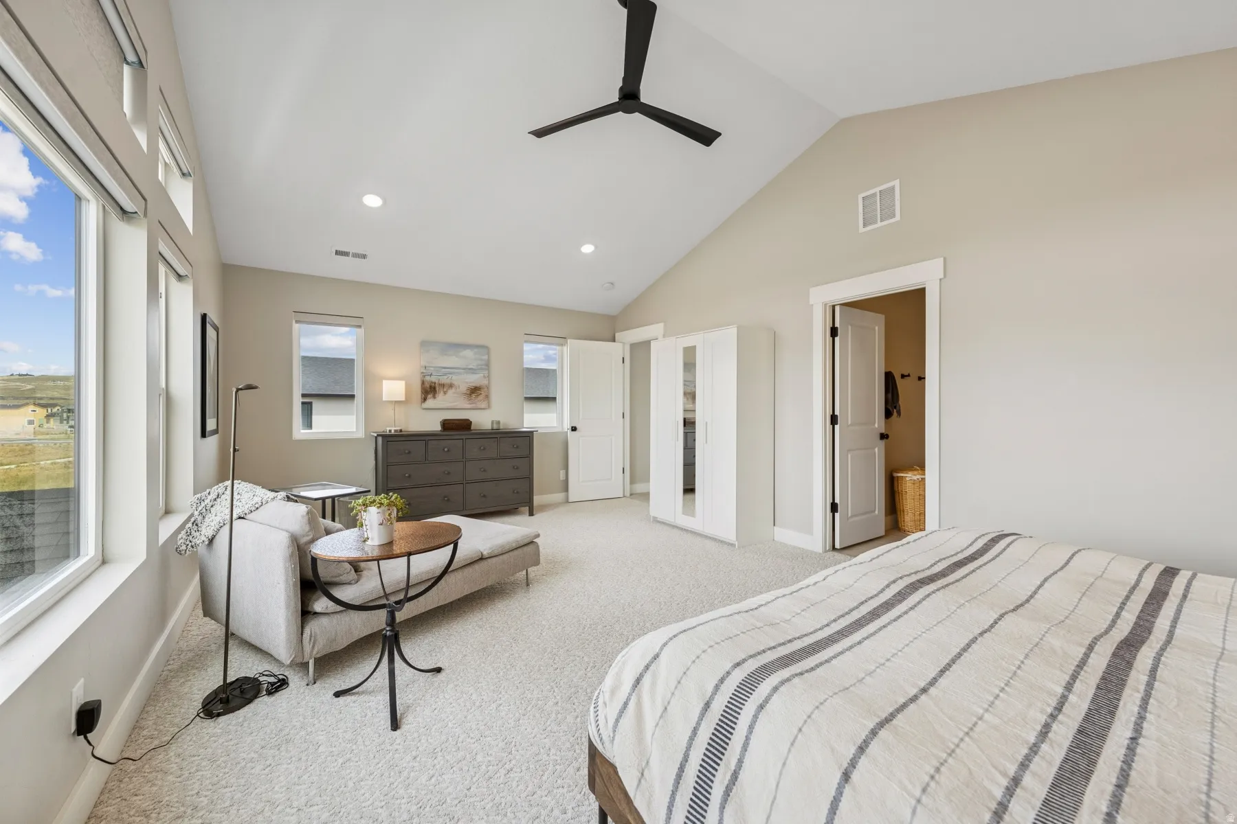 Vaulted ceiling, recessed lighting, ceiling fan, multiple windows, and light-toned carpeting