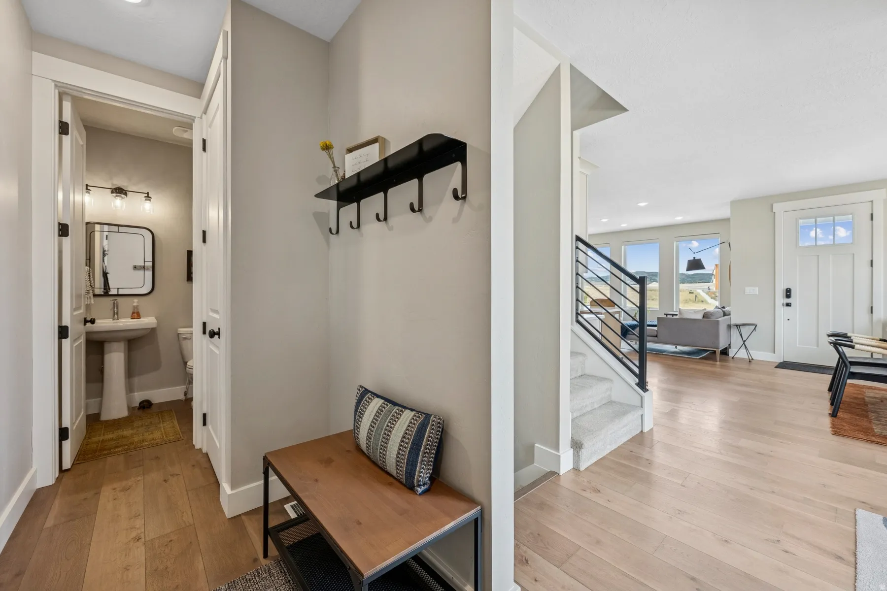 Hardwood-finish flooring throughout, bright paint finishes, staircase with black metal railing, pedestal sink in a powder room, and recessed lighting