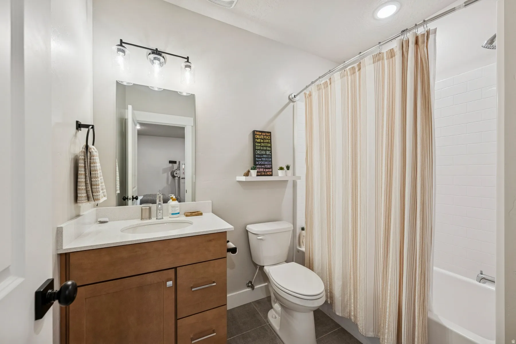Built-in vanity with wood-finish cabinetry, a white countertop, and an undermount sink