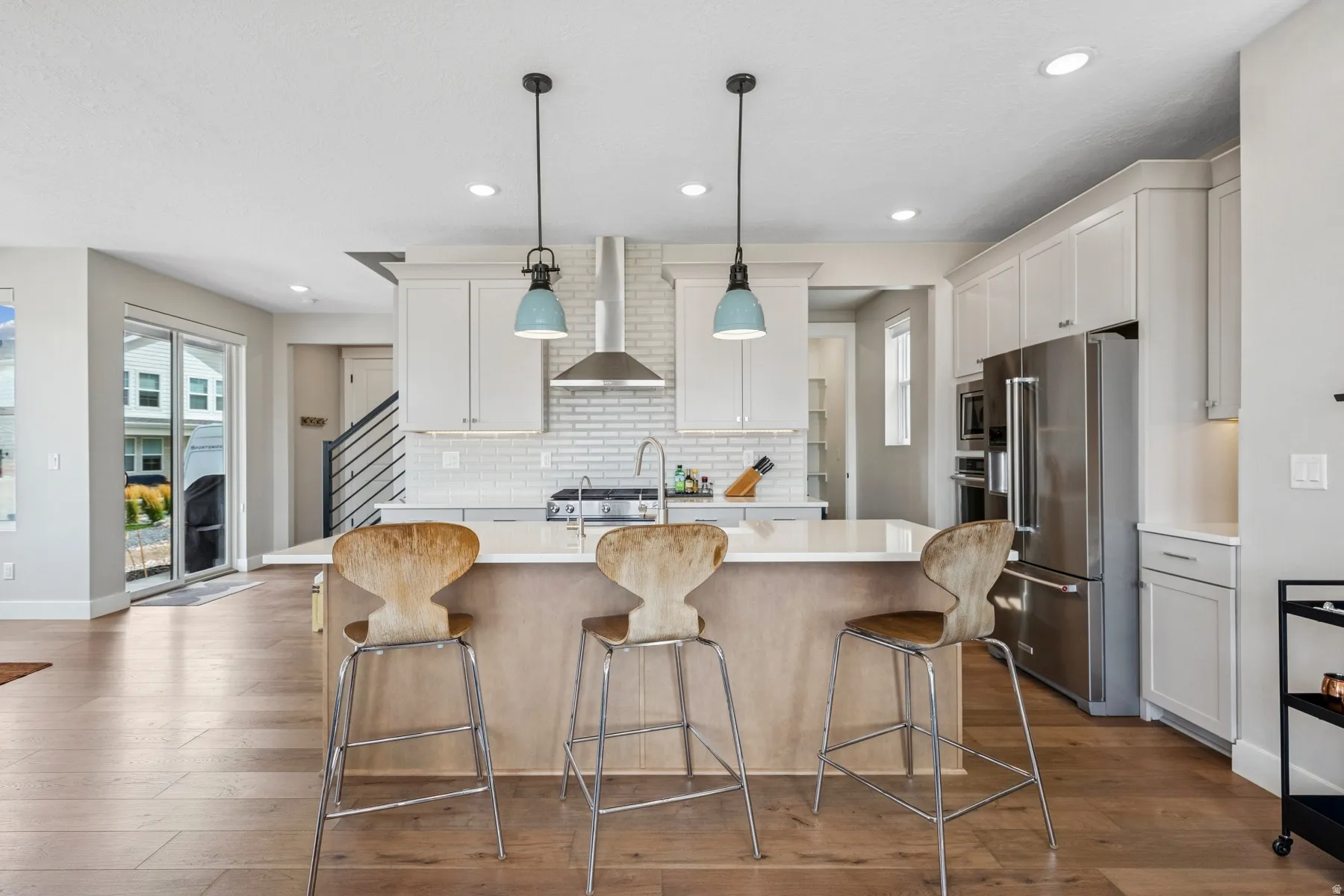 Kitchen featuring a central island with countertop seating, white cabinetry, stainless steel appliances, and wood-finish flooring