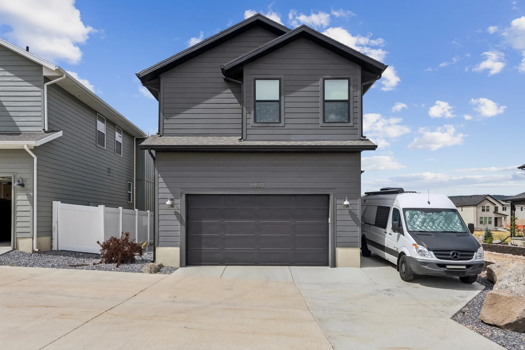 Two-story exterior with dark gray siding, an integrated garage, and a concrete driveway