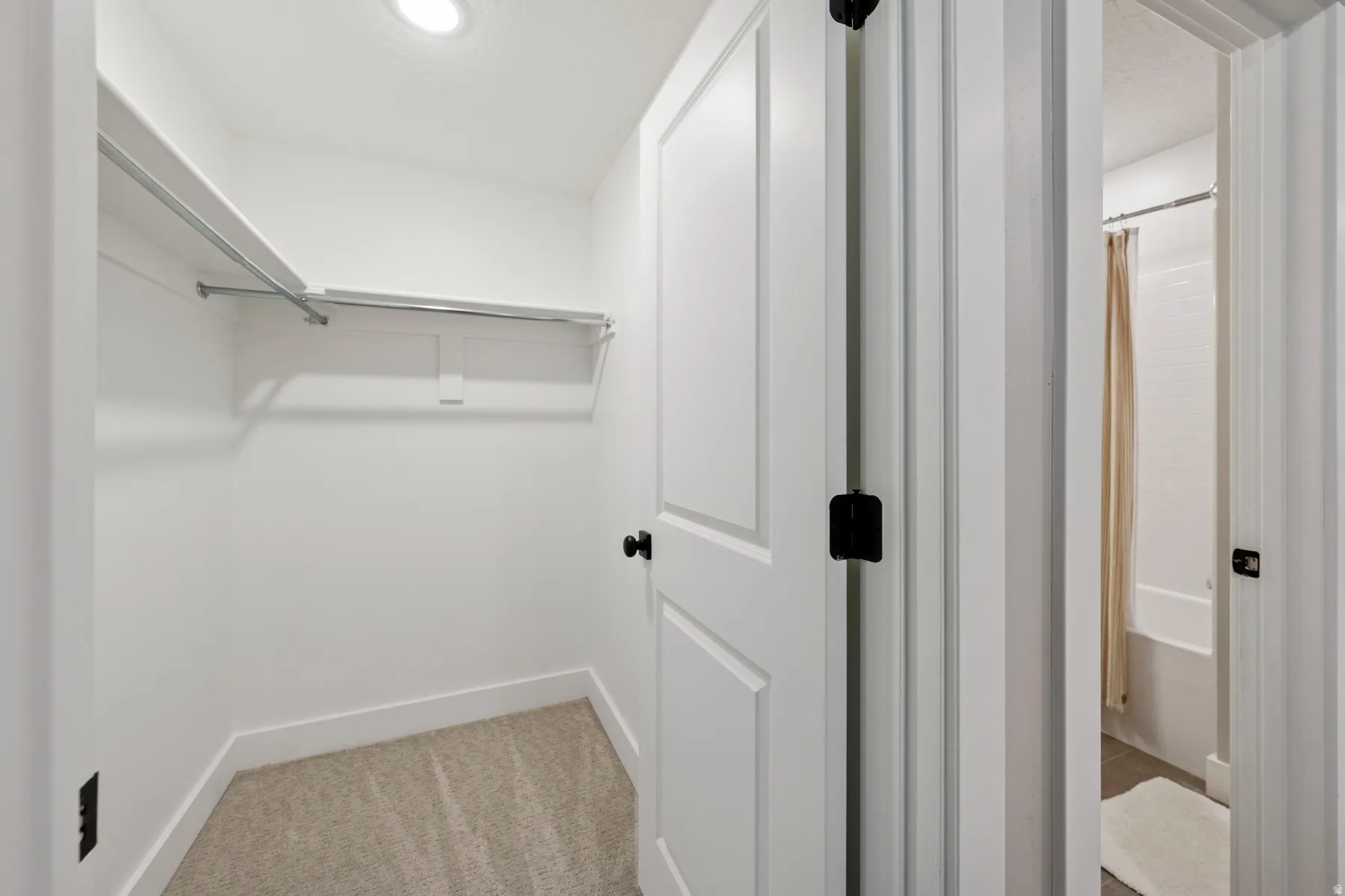 Recessed ceiling lighting, white interior doors, black door hardware, and light-colored carpet