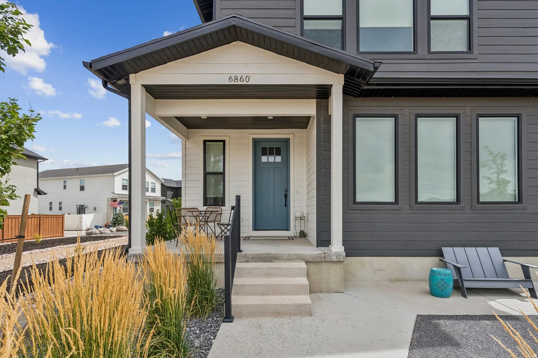 Covered front porch with white columns, concrete steps, and a blue entry door