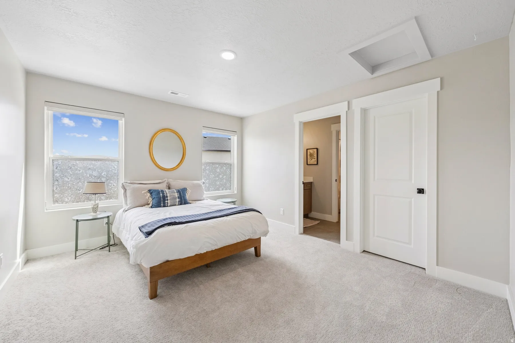 Recessed ceiling lighting, light gray wall tones, light gray carpet flooring, two paneled doors, and two windows with frosted lower panes