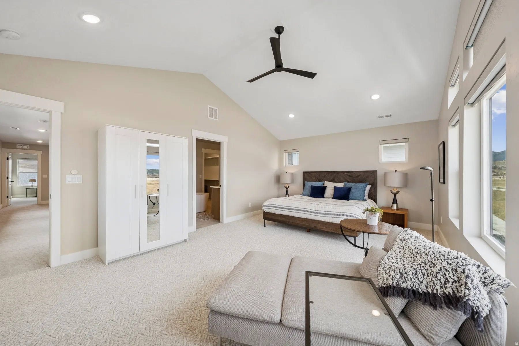 Vaulted ceiling with a black ceiling fan, recessed lighting, and large windows