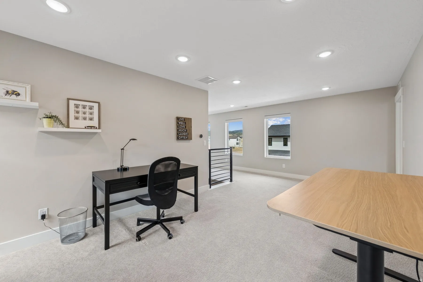 Recessed ceiling lighting, light gray wall paint, light-toned carpeting, and a modern black metal railing