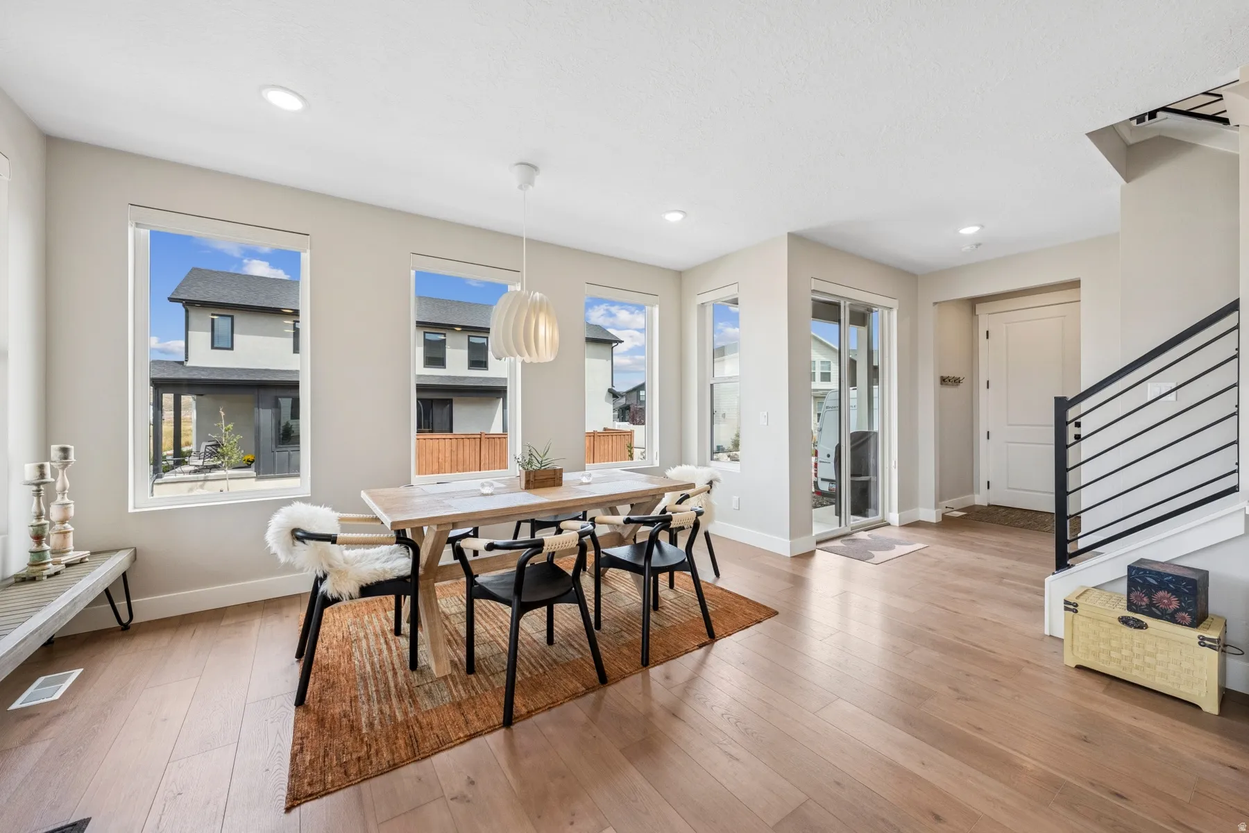 Expansive wood-finish flooring, numerous windows, recessed lighting, white trim, and a modern stair railing