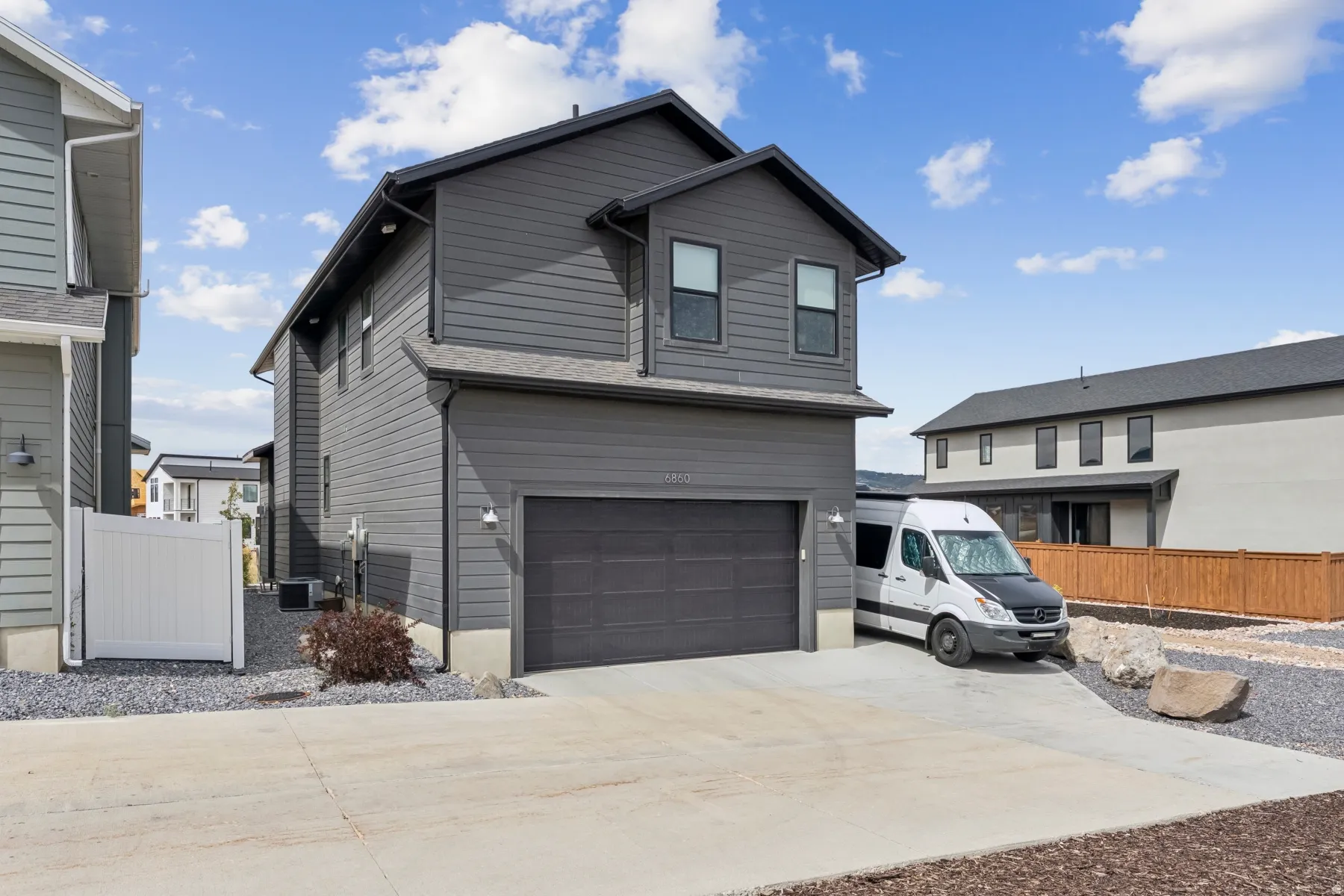 Contemporary multi-level exterior with dark horizontal siding, an attached two-car garage, and a concrete driveway