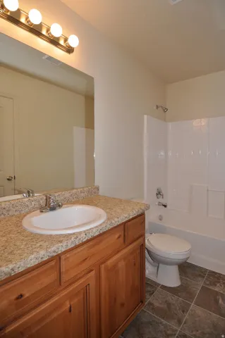 Full vanity with an integrated basin, granite-patterned countertop, and wood-finish cabinetry