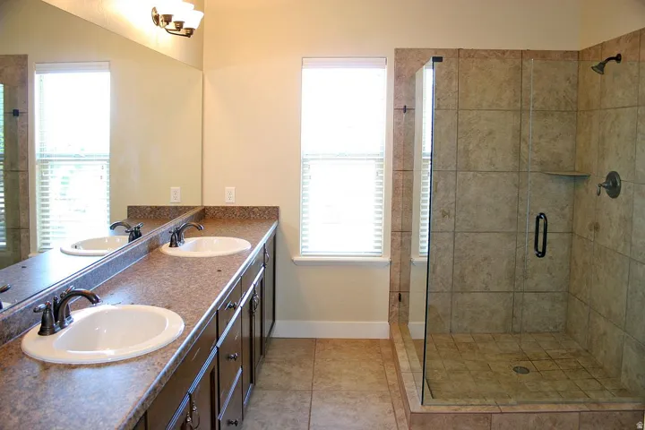 Dual vanity with integrated sinks, expansive mirror, and dark wood-finish cabinetry