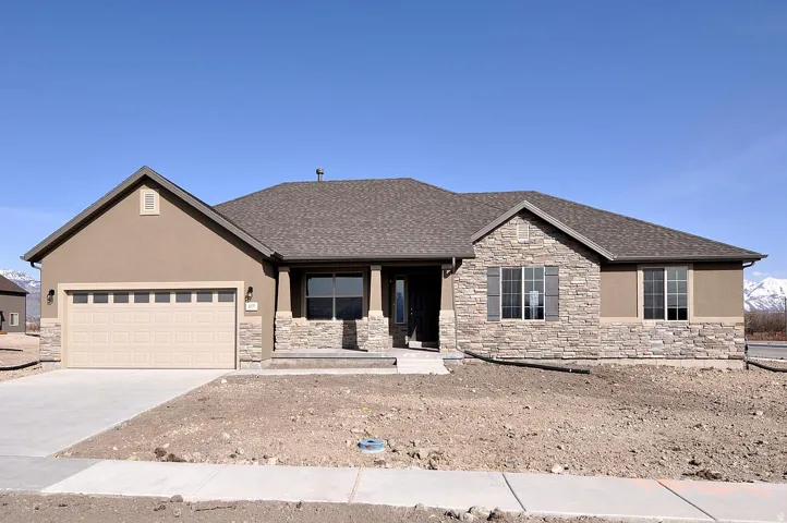 Stucco exterior with stone veneer accents, concrete driveway, attached garage, and a covered entry