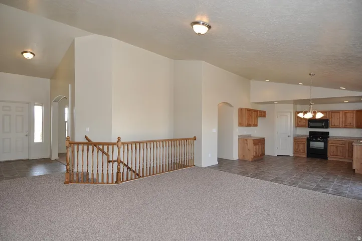 Vaulted ceiling, wood spindle railing, tiled entry, recessed lighting, wood-finish cabinetry