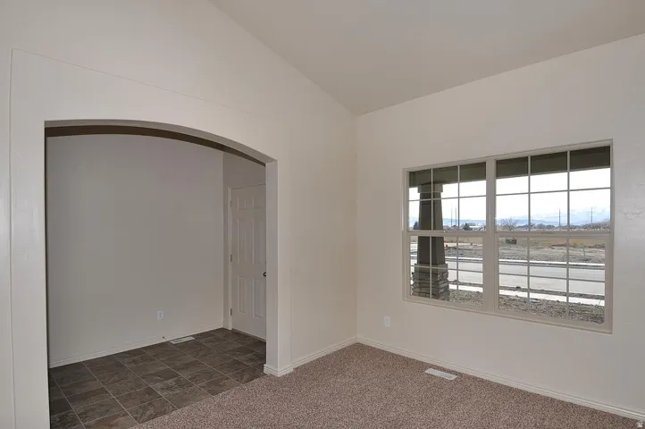 Arched entryway, neutral wall paint, carpeted flooring, tiled flooring, framed window