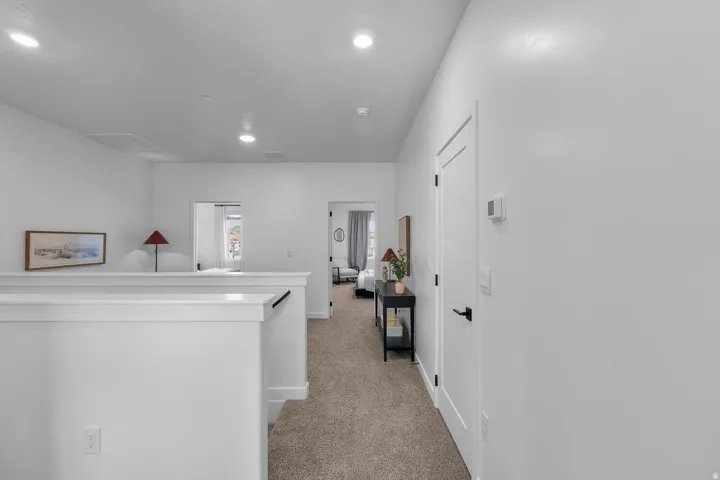 Carpeted hallway with recessed lighting, white walls, and contemporary doors featuring matte black hardware