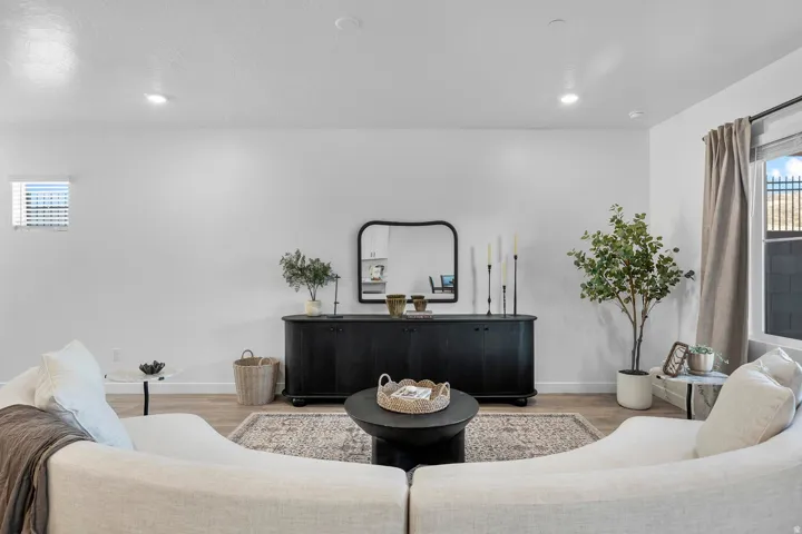 Recessed lighting illuminates the space, featuring wood-finish flooring and a window with blinds