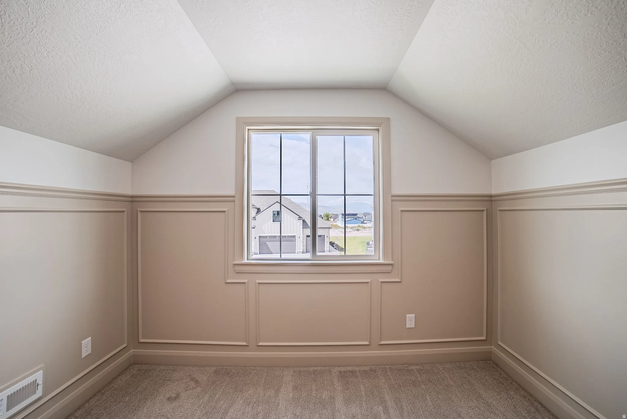 Window with muntins, wainscoting, vaulted ceiling, and carpet flooring